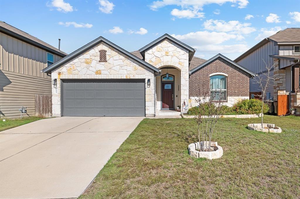 235 Limerick Road Buda, TX 78610 - Photo 1 of 11 French provincial home featuring stone siding, an attached garage, driveway, and a front yard