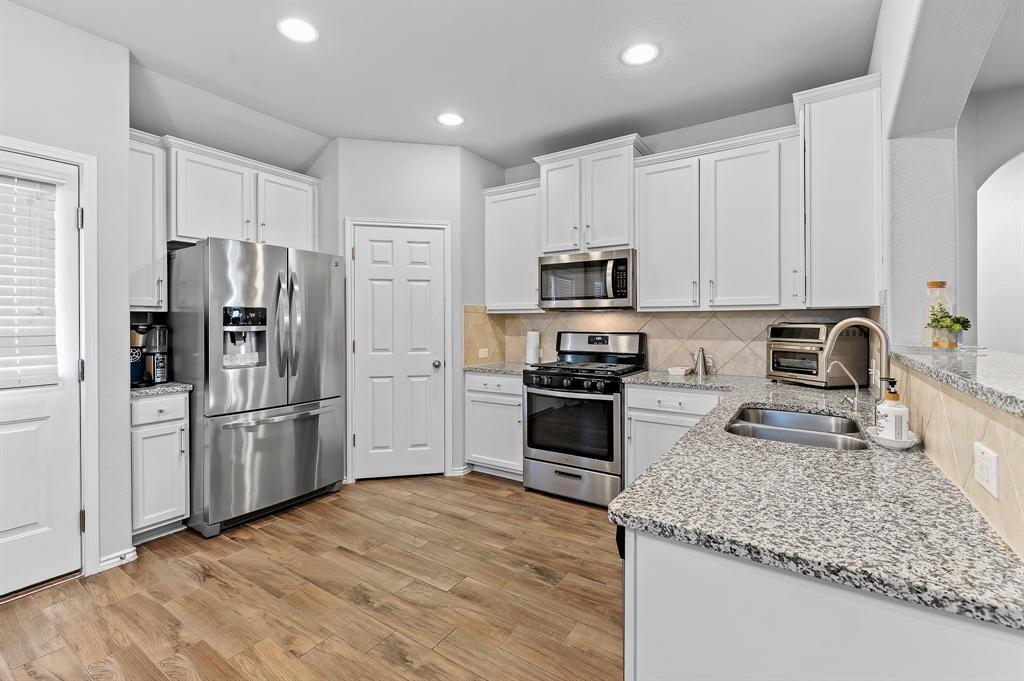 235 Limerick Road Buda, TX 78610 - Photo 2 of 11 Kitchen featuring light stone countertops, stainless steel appliances, white cabinets, and recessed lighting