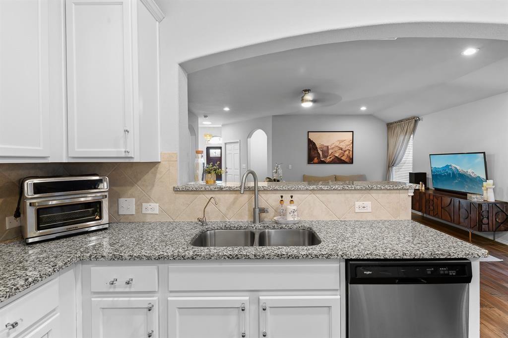 235 Limerick Road Buda, TX 78610 - Photo 7 of 11 Kitchen with white cabinetry, stainless steel dishwasher, light stone counters, ceiling fan, and backsplash