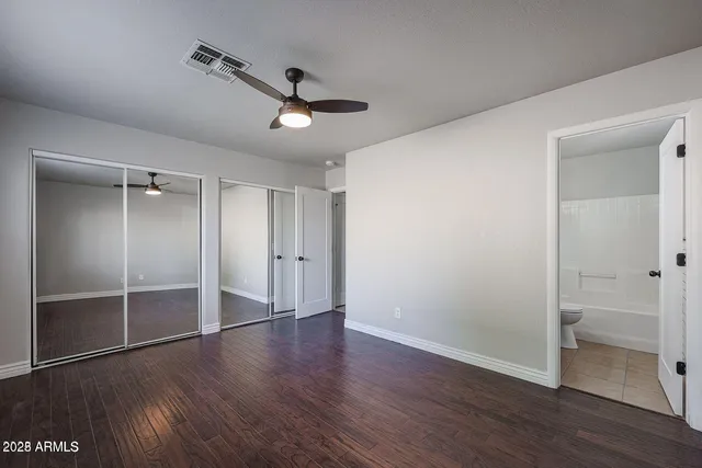 an empty room with wooden floor a ceiling fan and windows