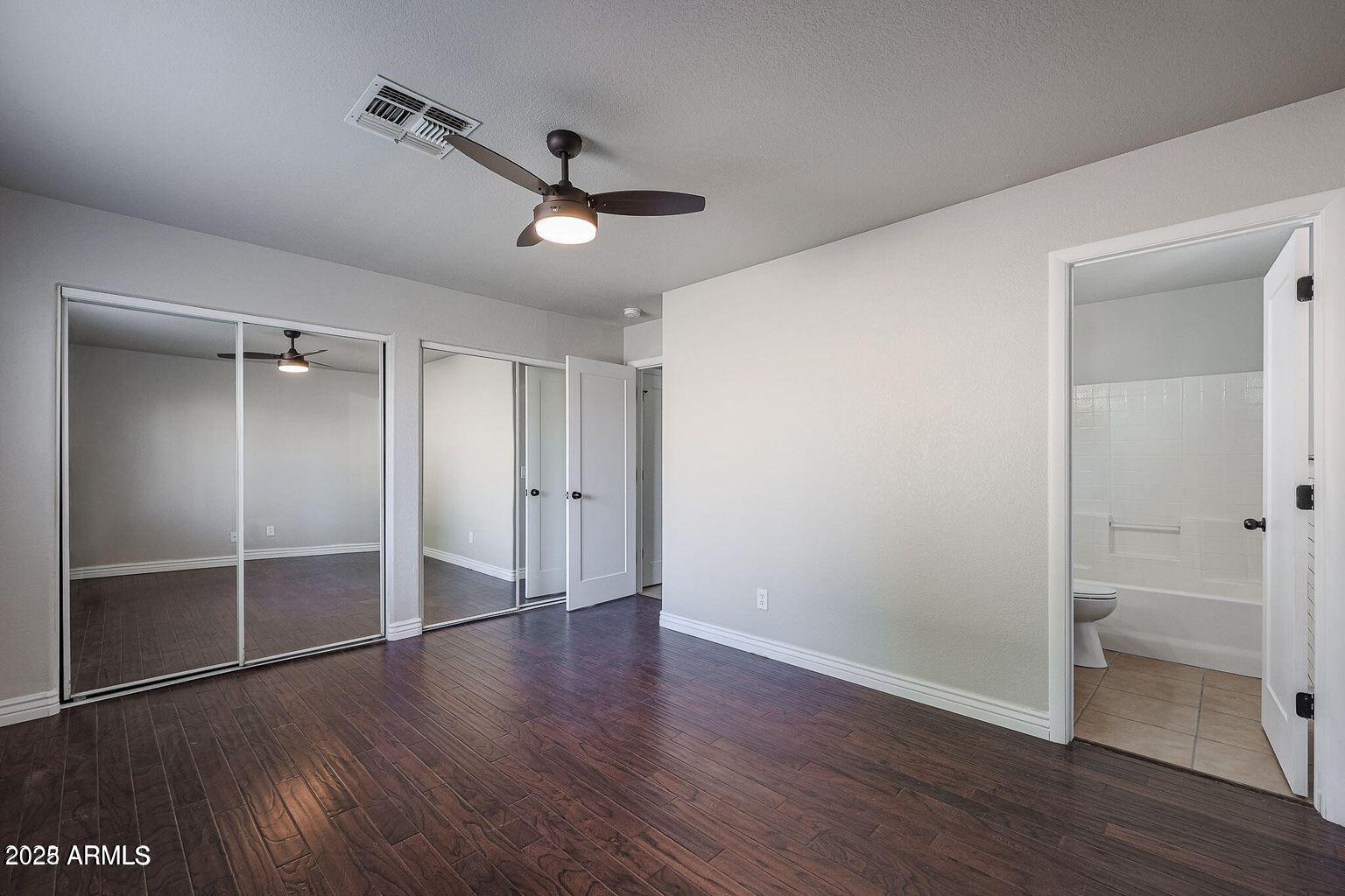 2134 East Robin Lane Phoenix, AZ 85024 - Photo 20 of 24 an empty room with wooden floor a ceiling fan and windows