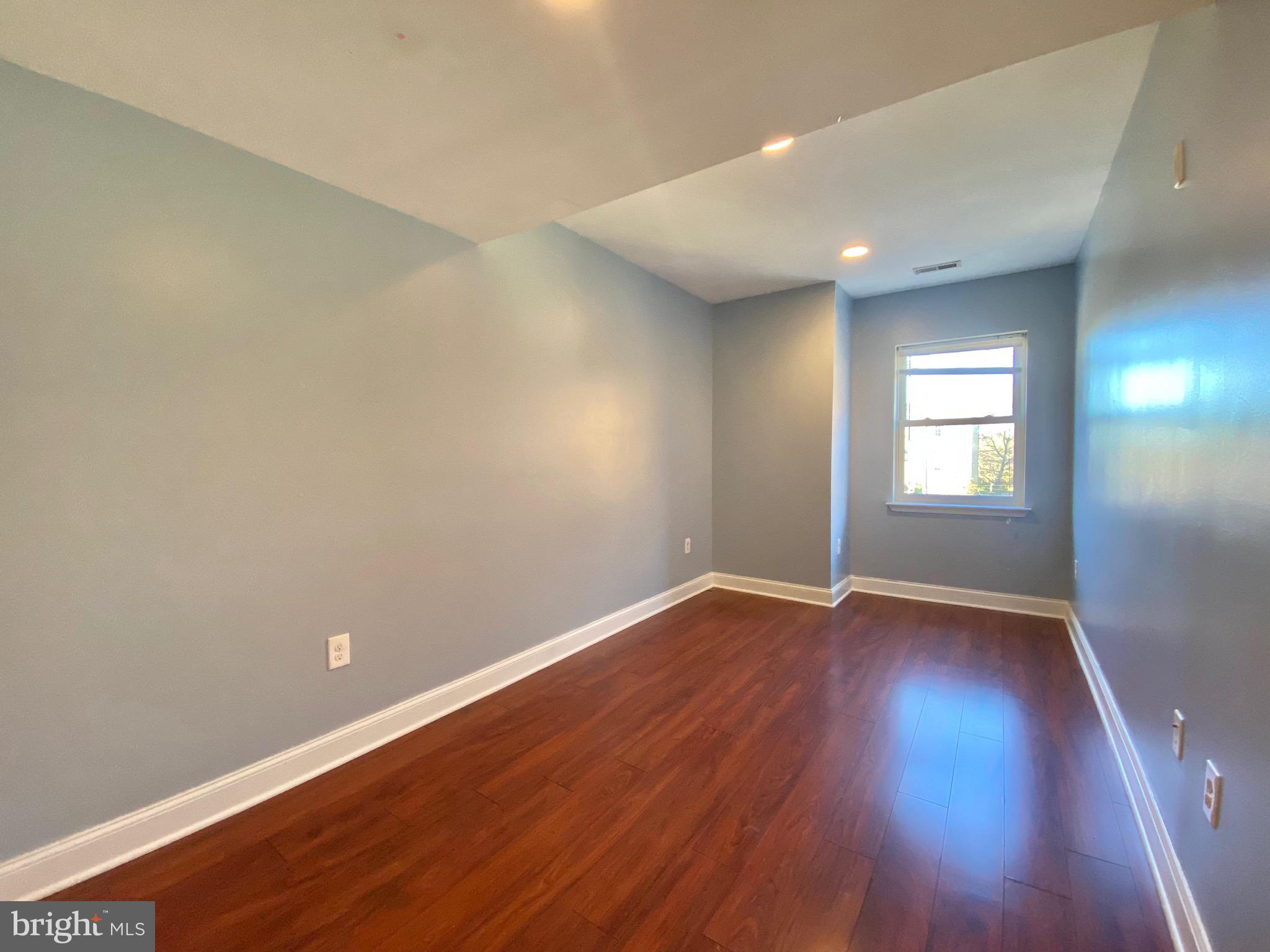 1419 North 17th Street, Unit C Philadelphia, PA 19121 - Photo 17 of 21 an empty room with wooden floor and windows