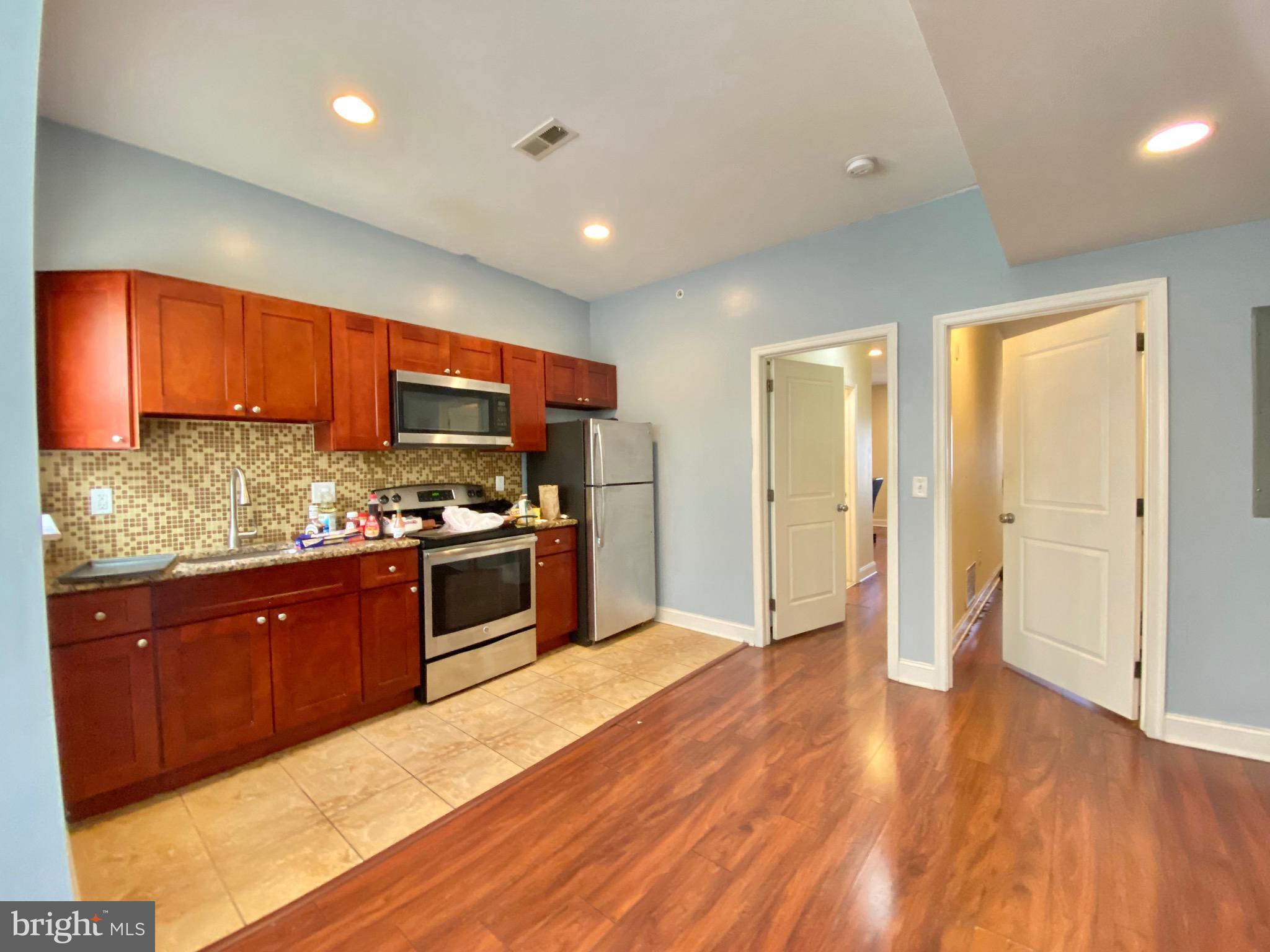 1419 North 17th Street, Unit C Philadelphia, PA 19121 - Photo 2 of 21 a kitchen with stainless steel appliances granite countertop a refrigerator a sink dishwasher a stove with wooden cabinets and floor