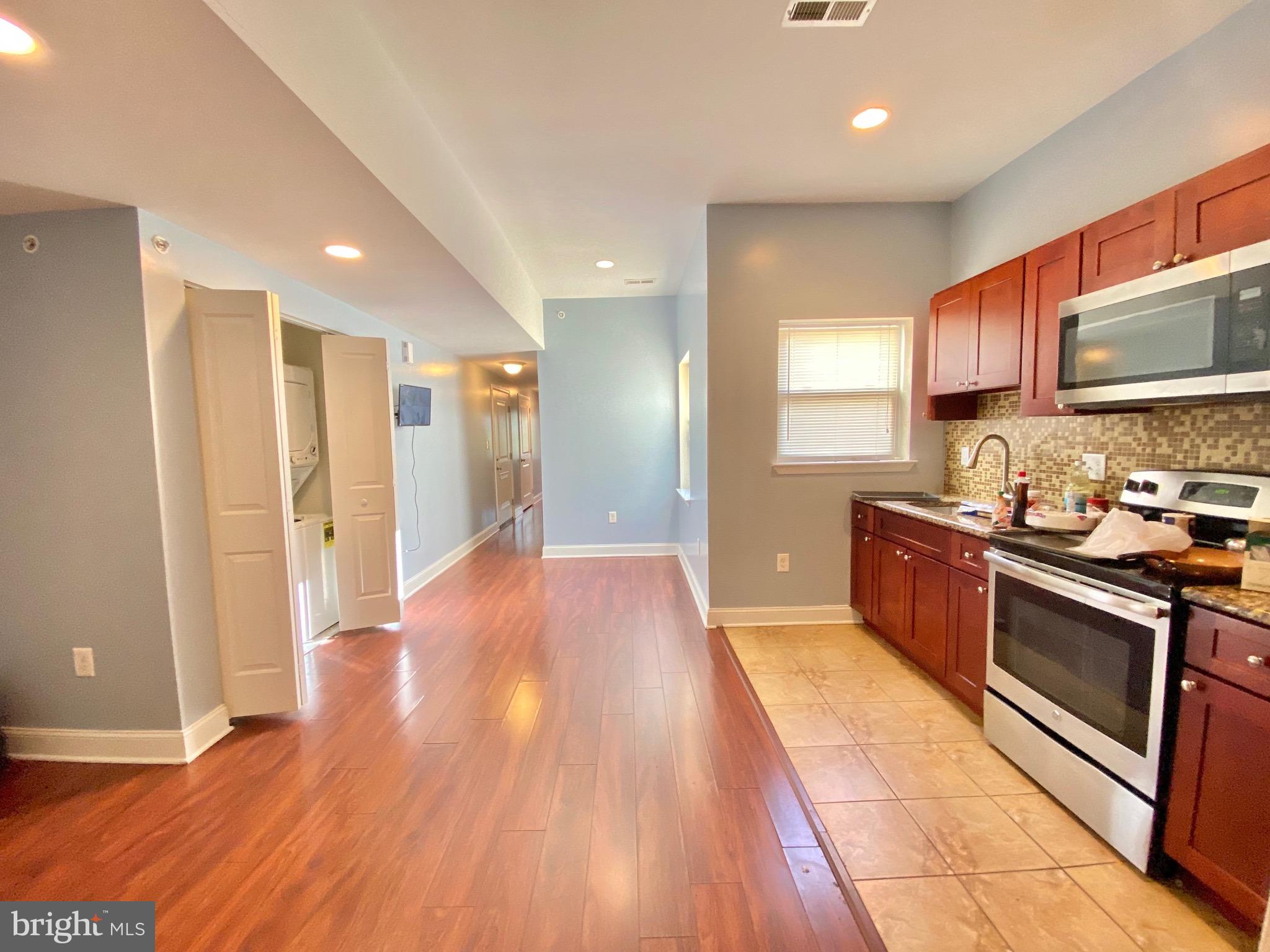1419 North 17th Street, Unit C Philadelphia, PA 19121 - Photo 4 of 21 a large kitchen with stainless steel appliances granite countertop a refrigerator and a stove top oven