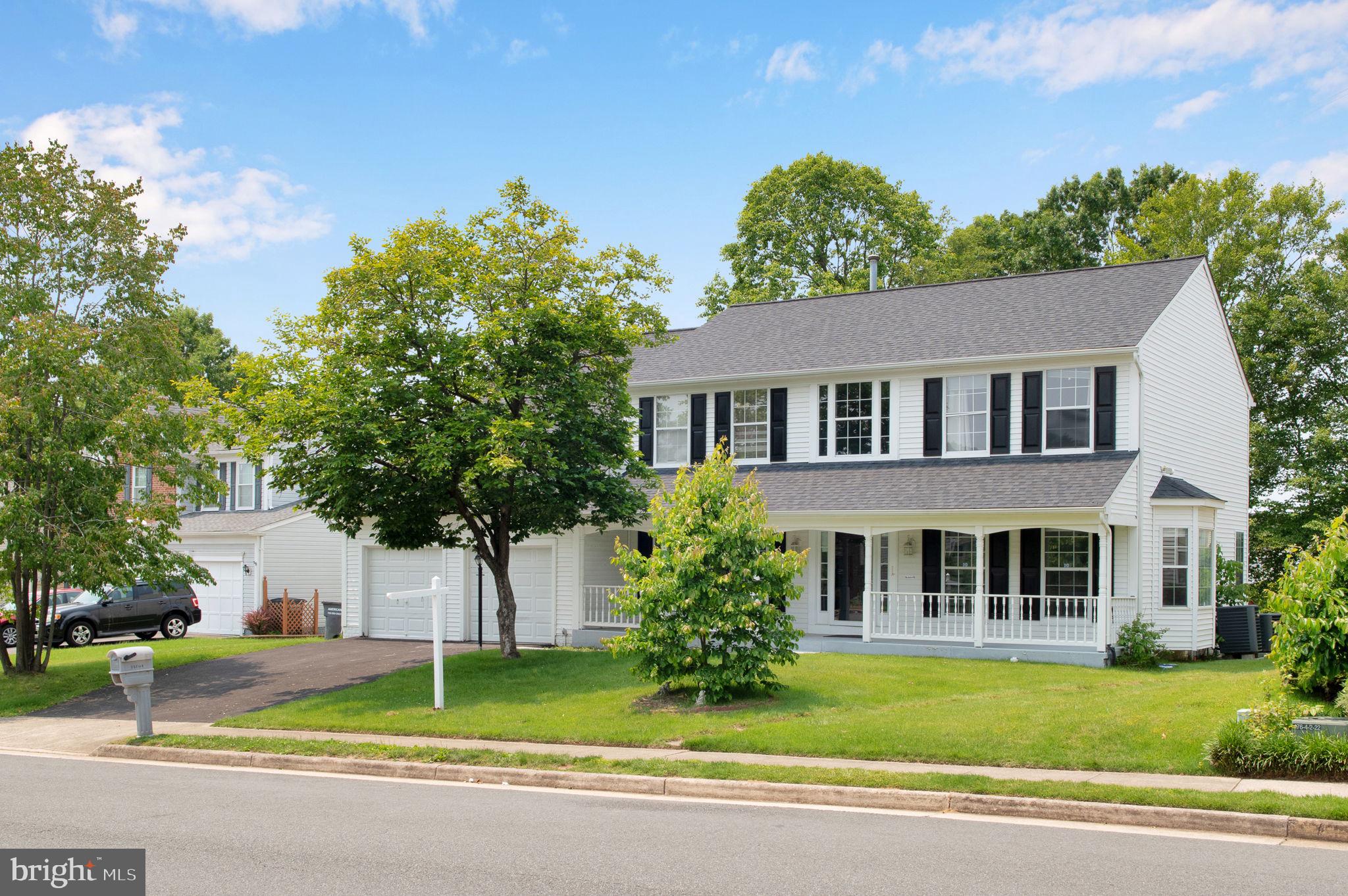a front view of a house with a garden and trees