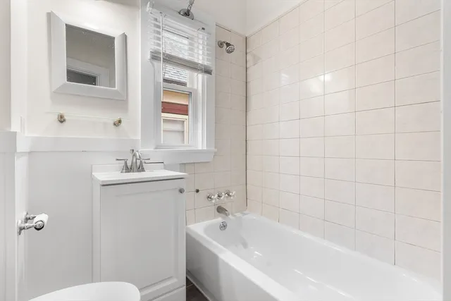 a white bath tub sitting next to a white sink and mirror