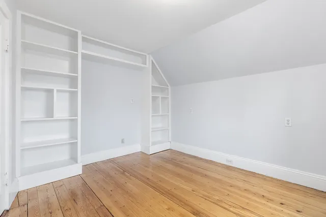 a view of an empty room with wooden floor and closet