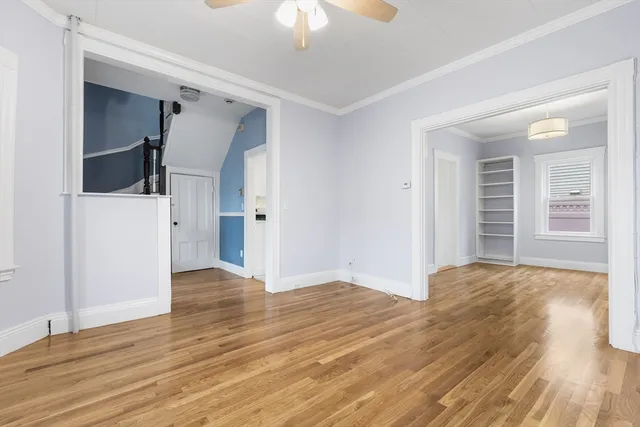a view of empty room with wooden floor and fan
