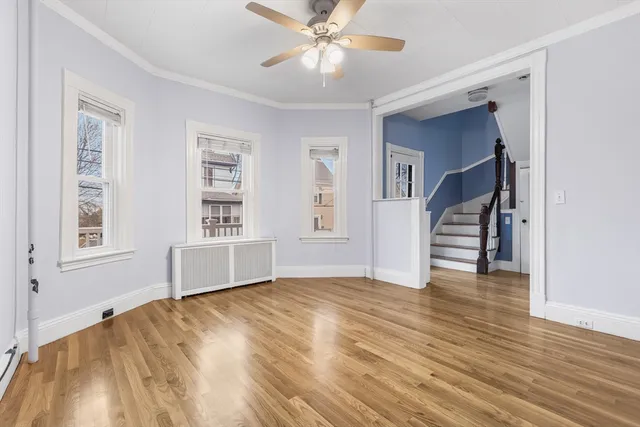 a view of empty room with wooden floor and fan