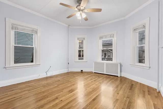 a view of an empty room with window and wooden floor