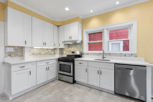 a kitchen with granite countertop white cabinets sink and window