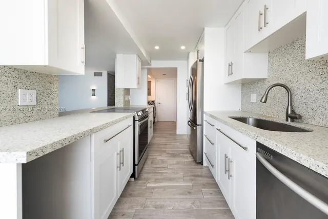 a large kitchen with stainless steel appliances granite countertop a lot of counter space and a sink
