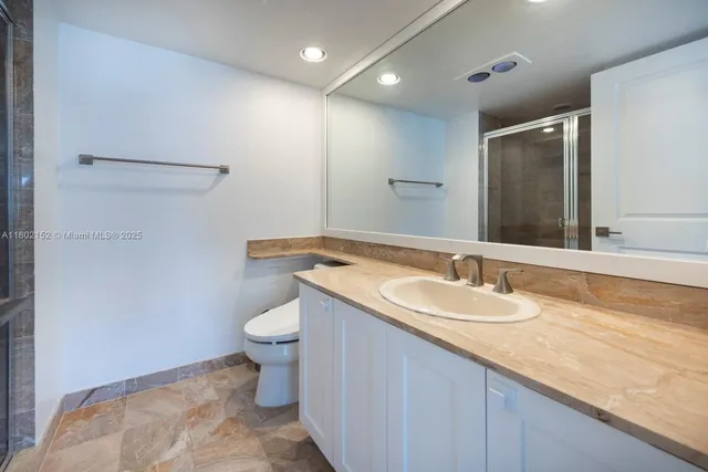 a bathroom with a granite countertop sink a toilet and a mirror
