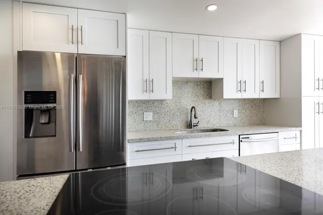 a kitchen with granite countertop a refrigerator and a sink
