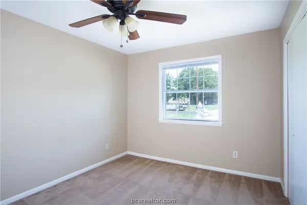 an empty room with a window and a fan