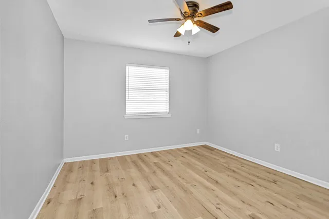 an empty room with a window and a fan