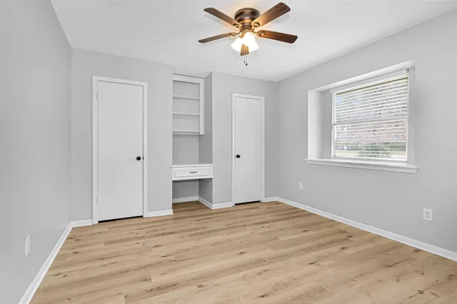 a view of empty room with wooden floor and fan