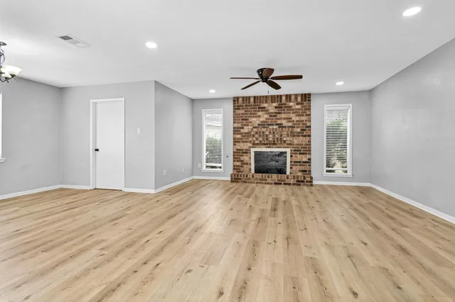 a view of empty room with wooden floor fireplace and window