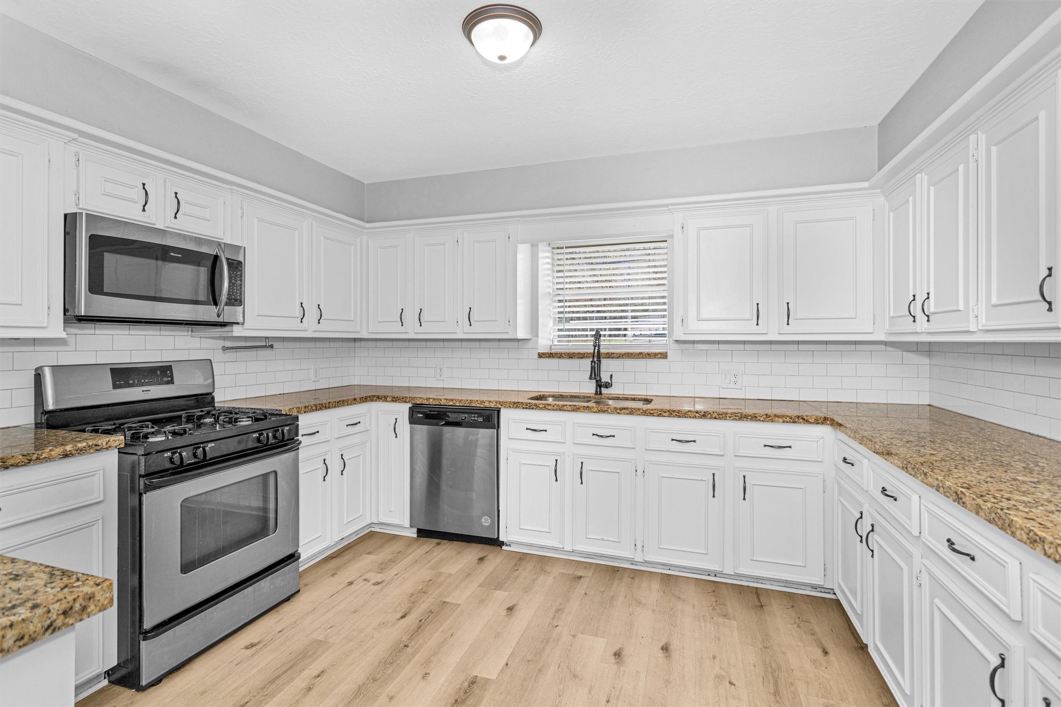 4655 Old Anderson Lane Conroe, TX 77304 - Photo 6 of 23 a kitchen with granite countertop a sink cabinets stainless steel appliances and a wooden floor