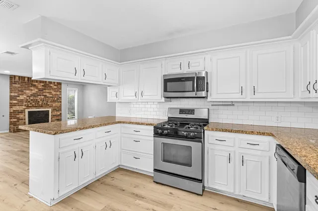 a kitchen with cabinets stainless steel appliances and wooden floor
