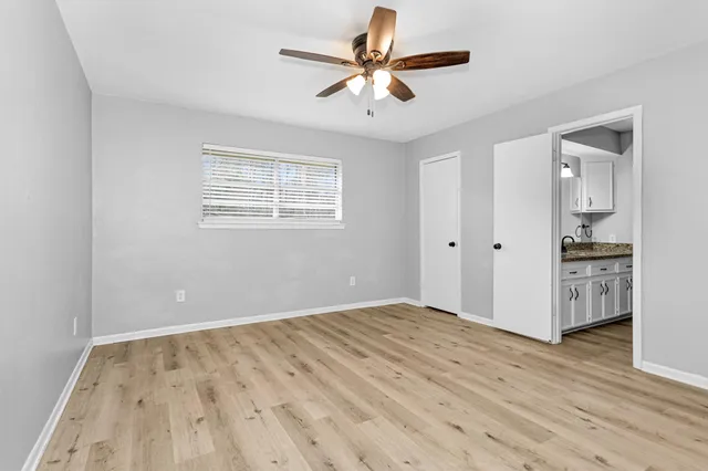 a view of empty room with wooden floor and fan