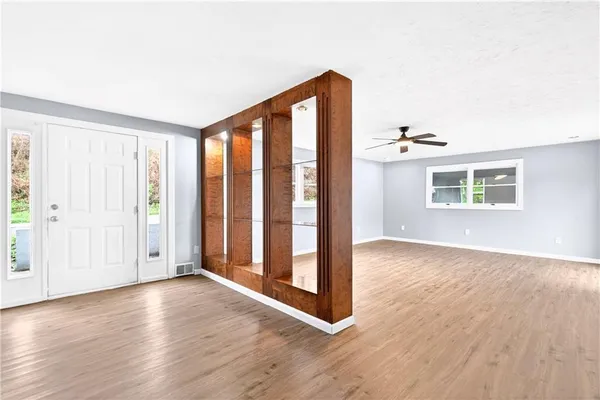 an empty room with wooden floor and windows