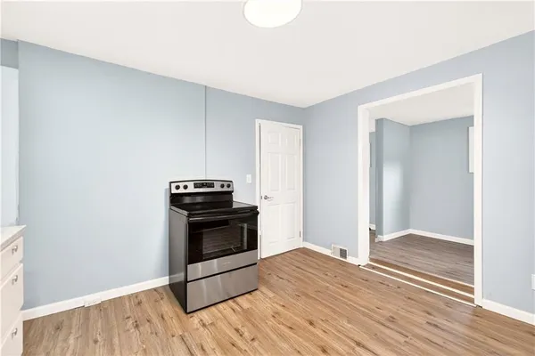 a kitchen with wooden floor and electronic appliances