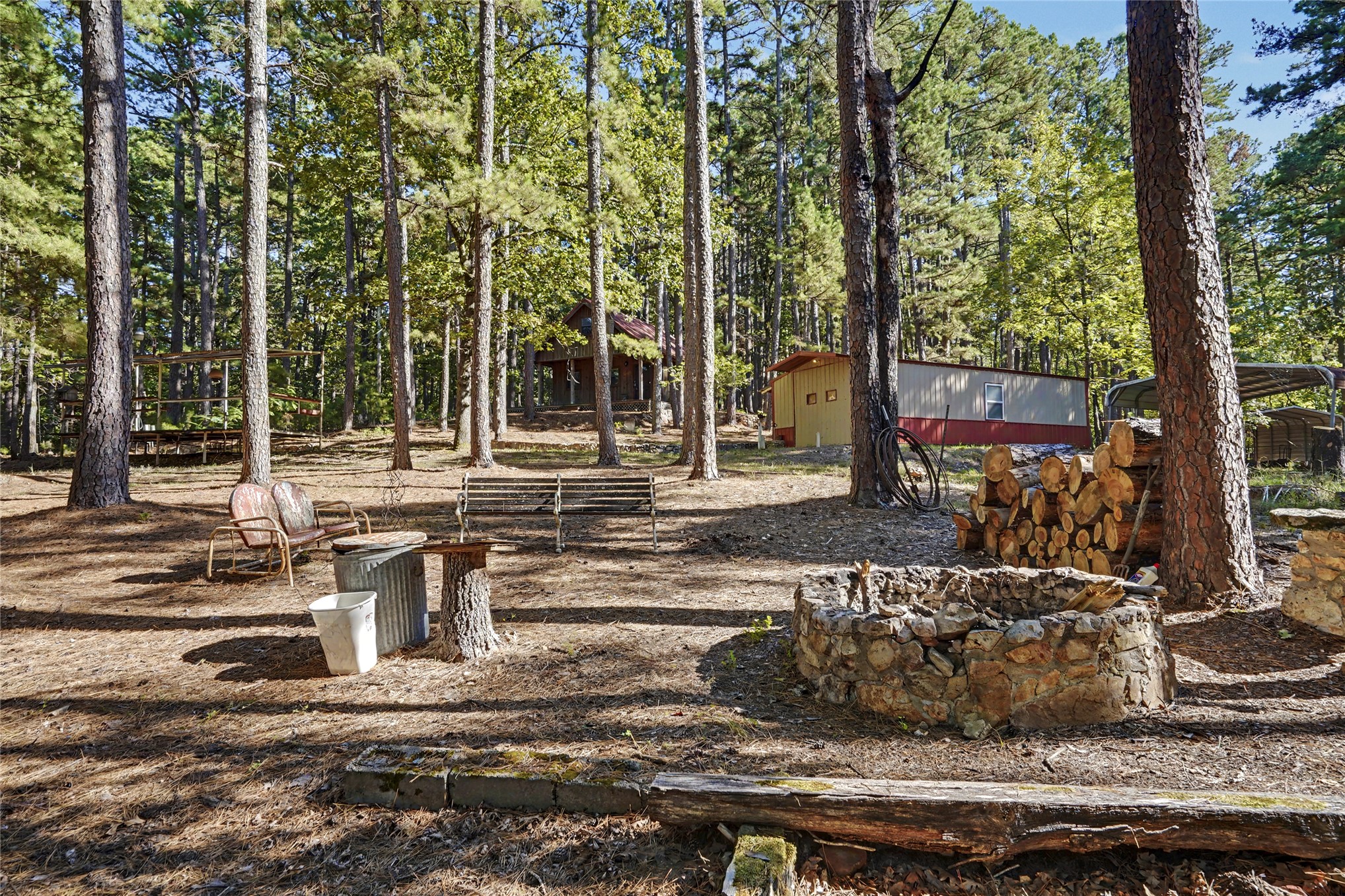 46420 South 590 Road Jay, OK 74346 - Photo 21 of 63 Wooded lot featuring a stone fire pit, mature trees, and multiple structures