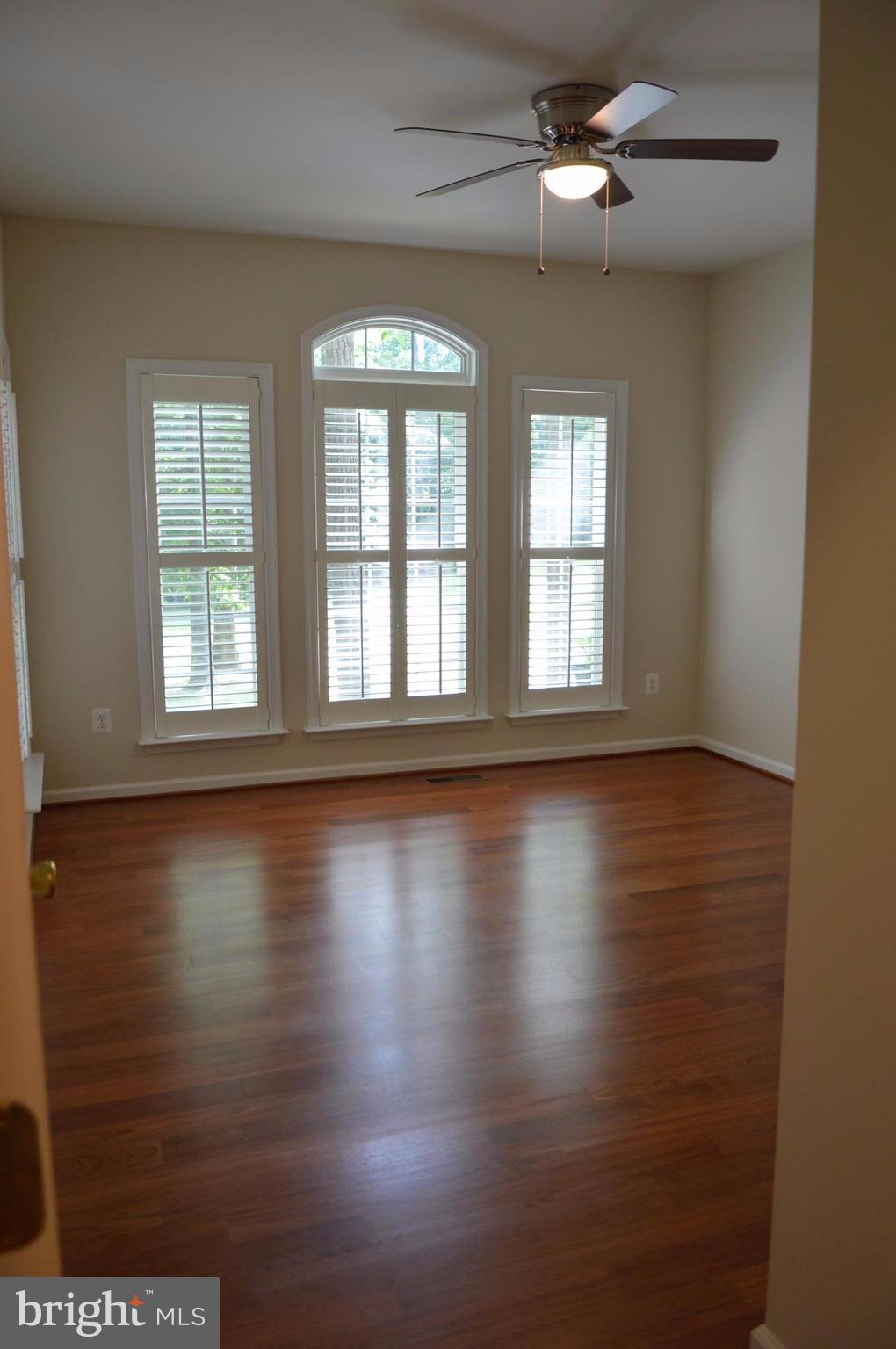 7536 Talbot Run Road Mount Airy, MD 21771 - Photo 13 of 22 an empty room with wooden floor and windows with curtains
