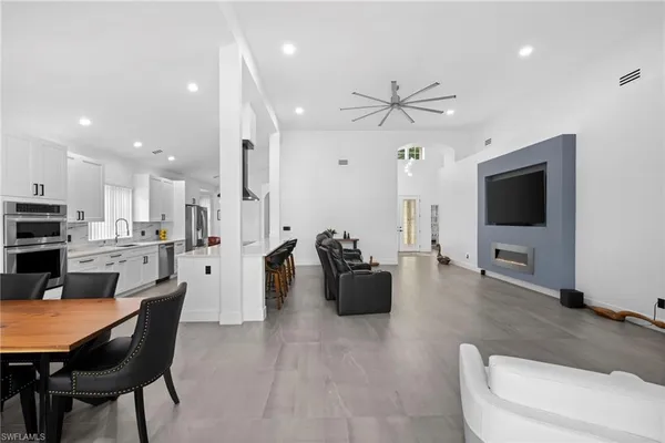 a living room with furniture a flat screen tv and kitchen view
