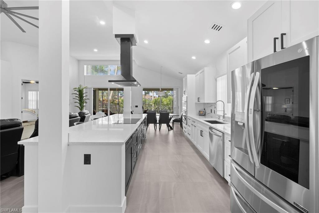 6903 Mauna Loa Lane Naples, FL 34113 - Photo 19 of 46 a kitchen with white cabinets and stainless steel appliances