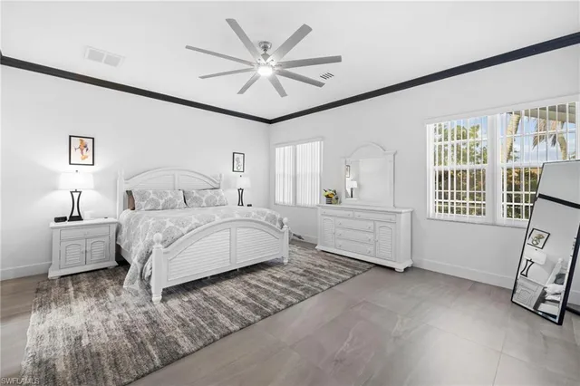 a bedroom with a large bed a chandelier and windows