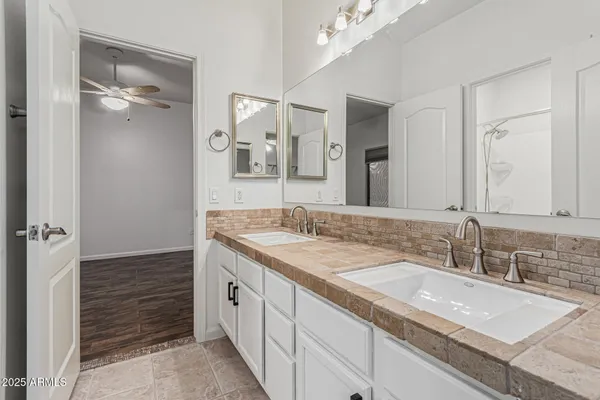 a bathroom with a granite countertop double vanity sink and mirror