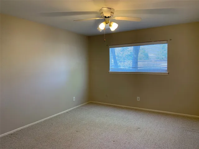 an empty room with a fan & a window