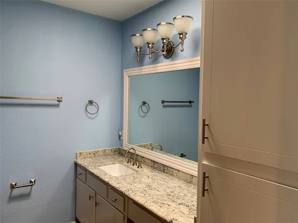 a bathroom with a granite countertop sink and a mirror