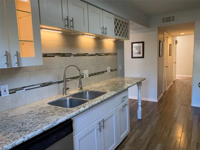 a kitchen with granite countertop a sink and wooden cabinets