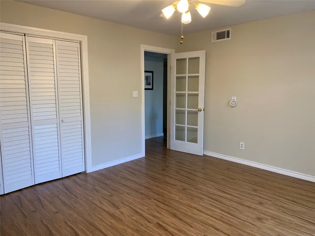 an empty room with wooden floor closet and windows