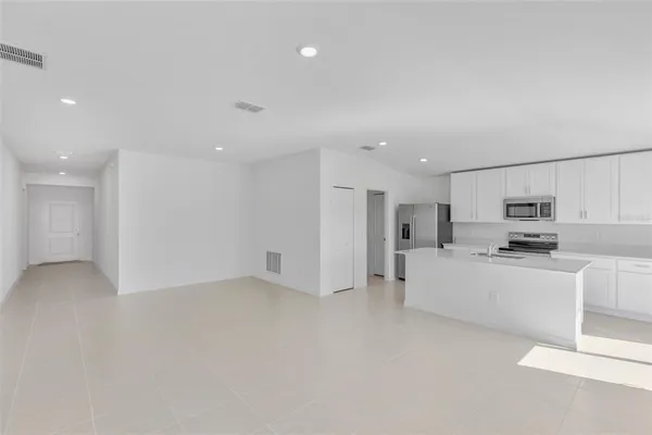 a large white kitchen with kitchen island a sink a stove and a refrigerator