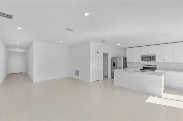 a large white kitchen with kitchen island a sink a stove and a refrigerator