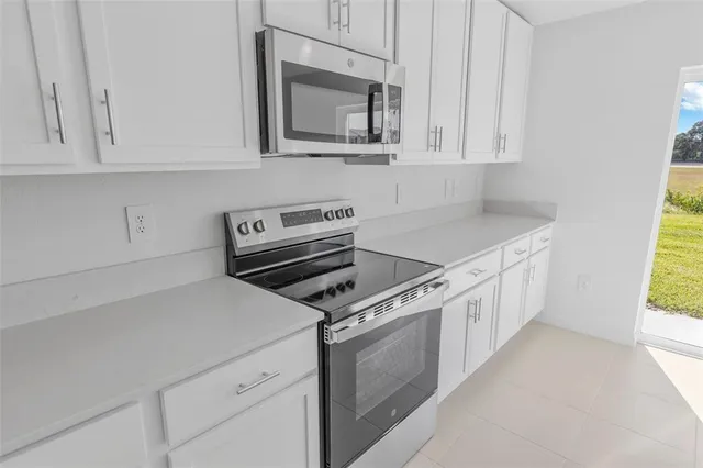 a kitchen with white cabinets and appliances