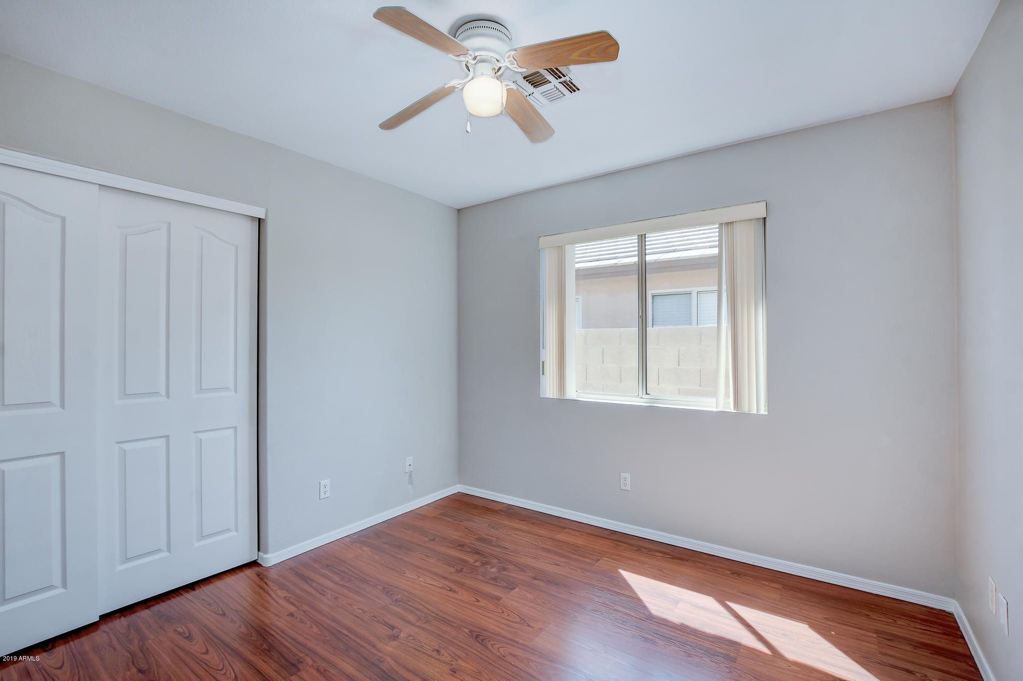 4404 East Rowel Road Phoenix, AZ 85050 - Photo 11 of 15 an empty room with wooden floor ceiling fan and windows