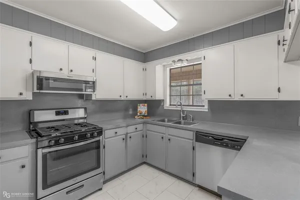 a kitchen with cabinets appliances a sink and a window