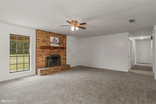 a view of an empty room with a fireplace and a fan