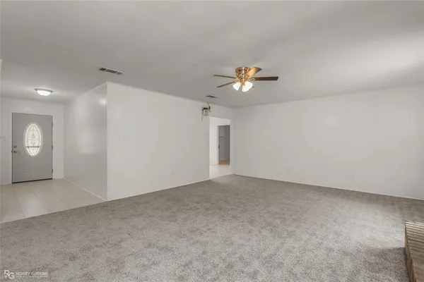 an empty room with windows and chandelier fan