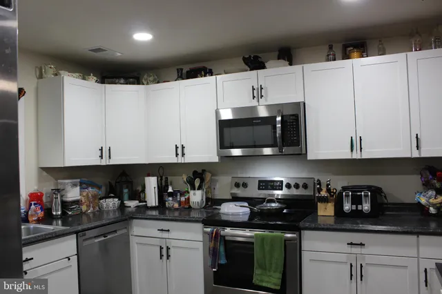 a kitchen with stainless steel appliances granite countertop white cabinets sink and a dishwasher