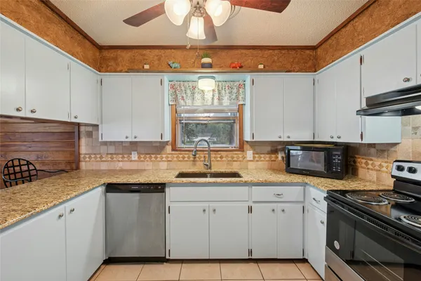 a kitchen with granite countertop a sink stainless steel appliances and cabinets