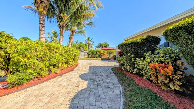 a backyard of a house with flower plants and large trees
