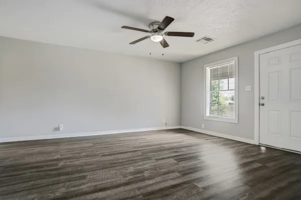 an empty room with wooden floor and windows