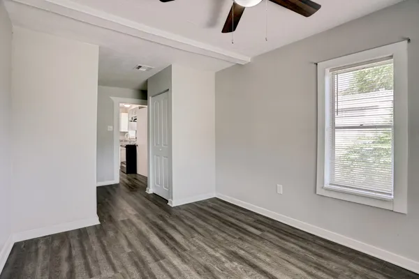 a view of an empty room with wooden floor and a window