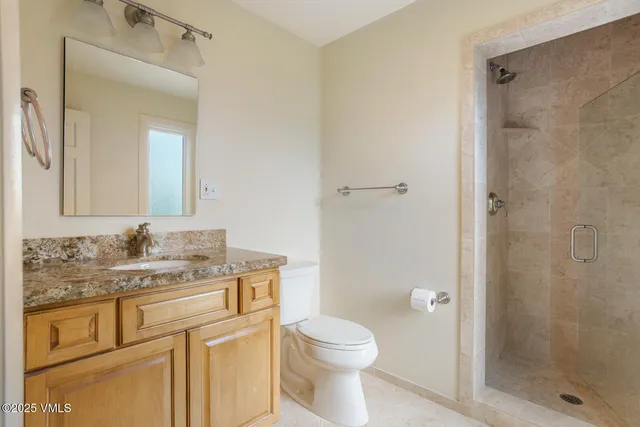 a bathroom with a granite countertop sink a mirror and a toilet